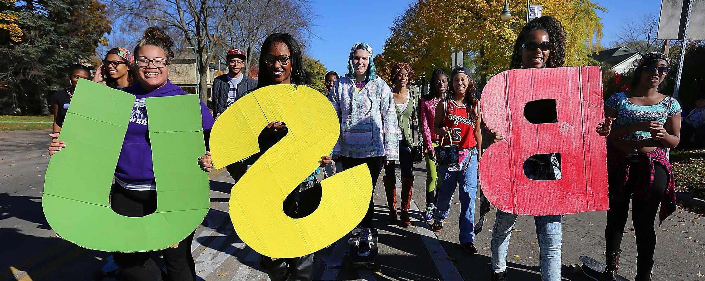 Students walk in the parade holding the letters BSU.